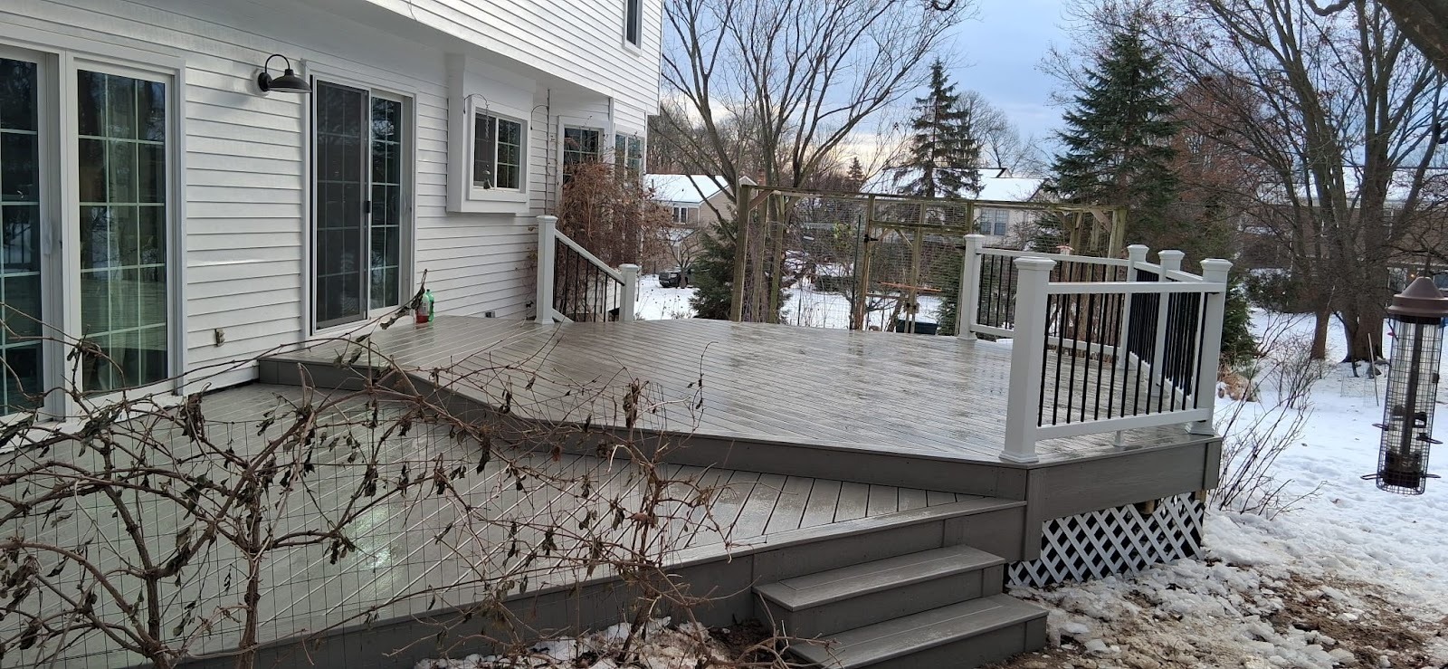 A finished rear deck with wood railings, stairs and a patio door on the house.